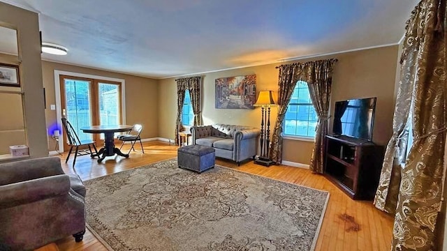 living room with ornamental molding, plenty of natural light, and light wood-type flooring