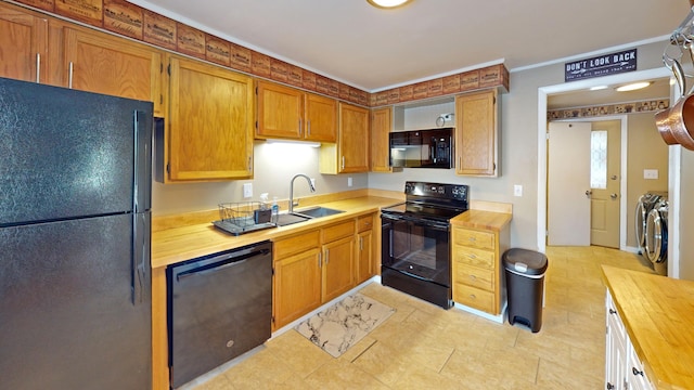 kitchen featuring washer and dryer, sink, ornamental molding, and black appliances