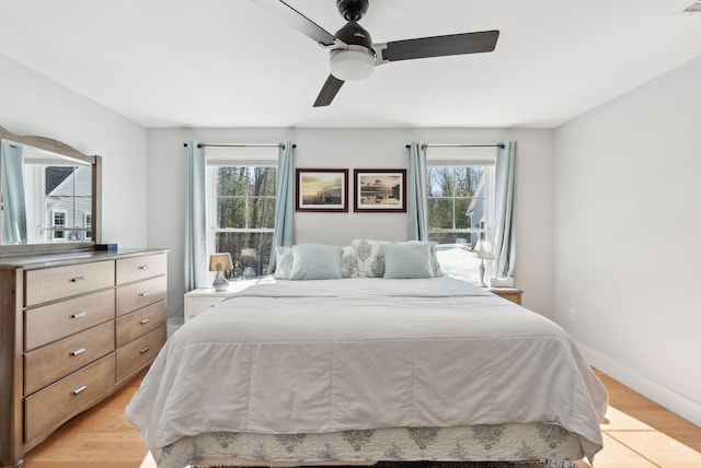 bedroom with light wood finished floors, ceiling fan, and baseboards