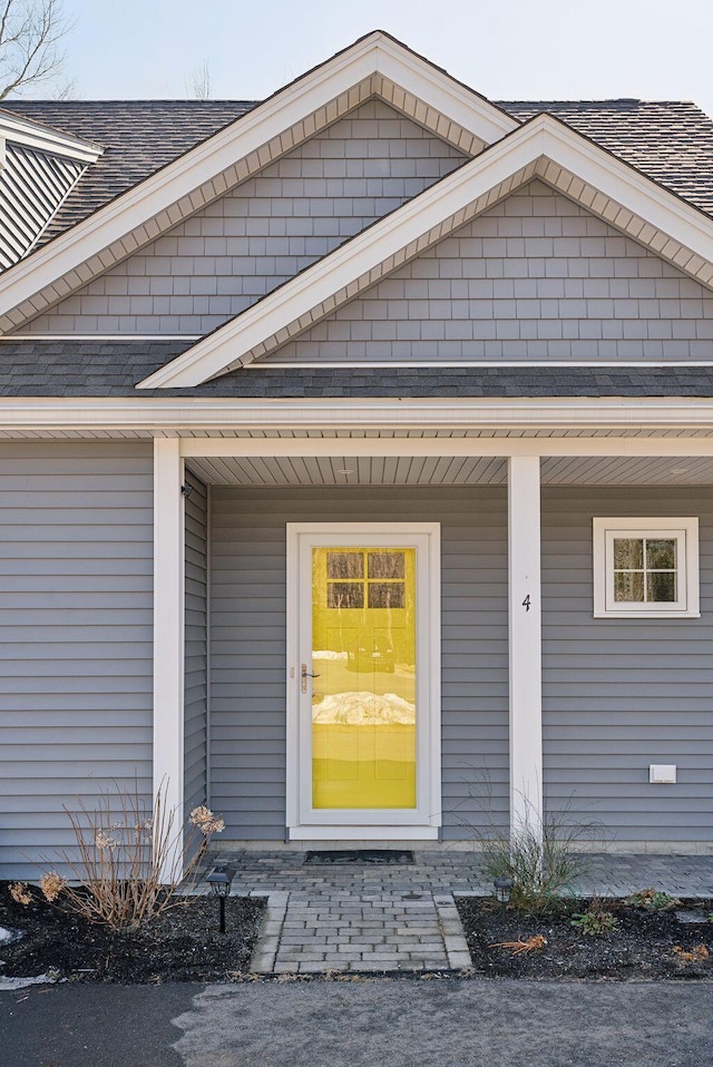 doorway to property featuring roof with shingles