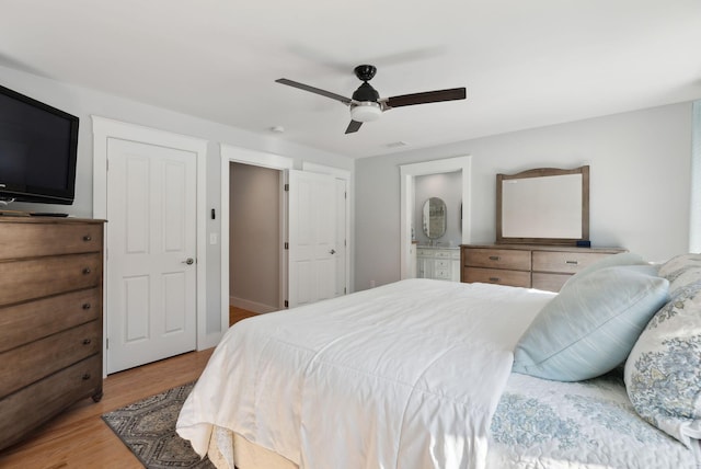 bedroom featuring visible vents, connected bathroom, a ceiling fan, and wood finished floors