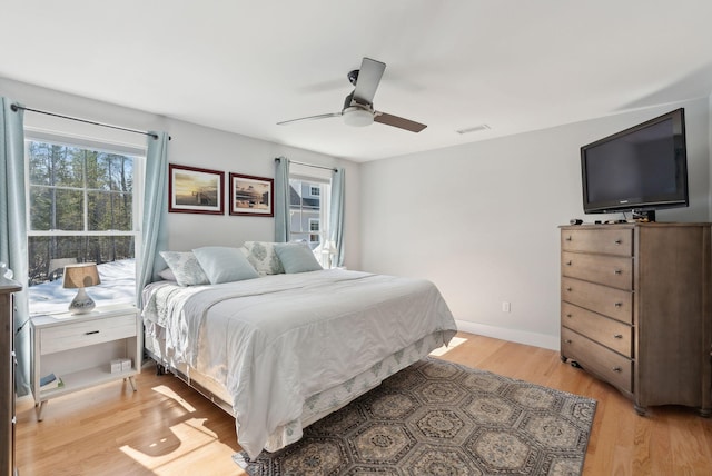 bedroom with visible vents, multiple windows, a ceiling fan, and light wood finished floors