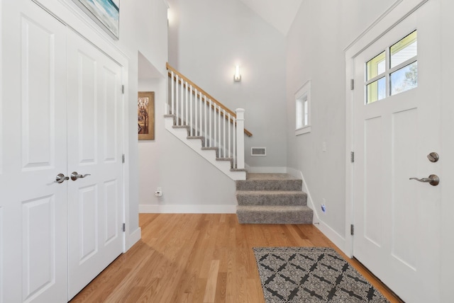 entryway with visible vents, stairs, light wood-type flooring, and baseboards