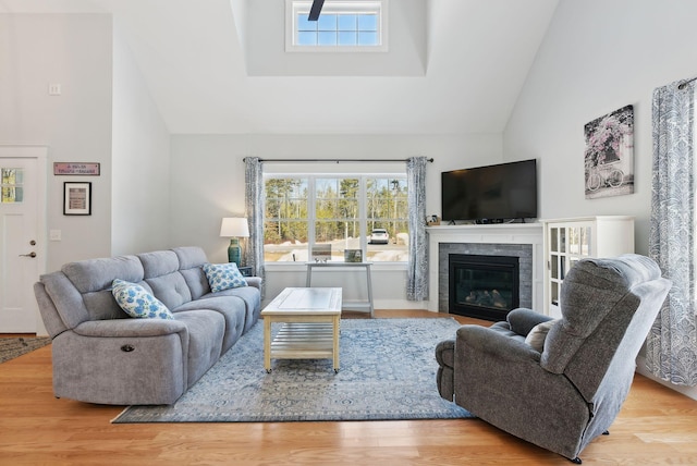 living area with high vaulted ceiling, wood finished floors, and a fireplace