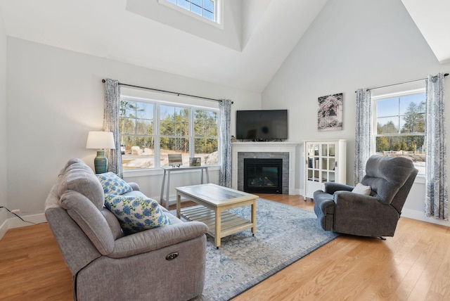 living room featuring high vaulted ceiling, plenty of natural light, wood finished floors, and a tile fireplace