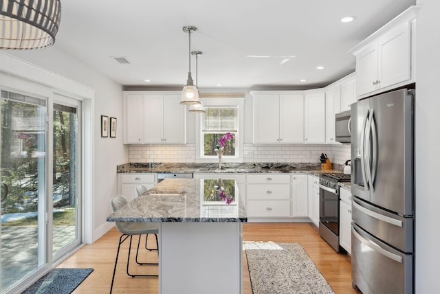 kitchen with light wood finished floors, appliances with stainless steel finishes, white cabinetry, and a sink