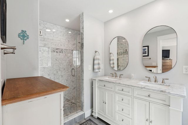 bathroom featuring double vanity, a shower stall, and a sink