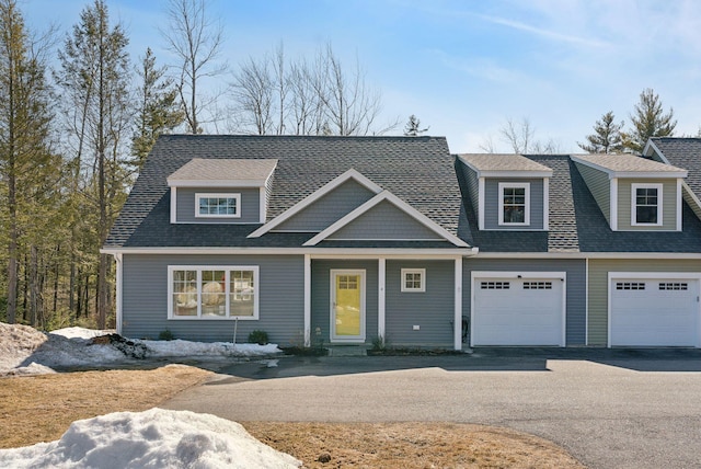 view of front of home featuring an attached garage, driveway, and a shingled roof