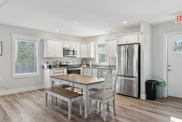 kitchen featuring white cabinets, appliances with stainless steel finishes, and light wood-style flooring