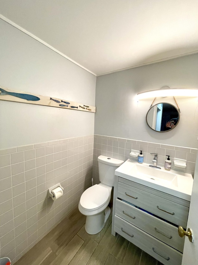 bathroom with vanity, ornamental molding, tile walls, and toilet