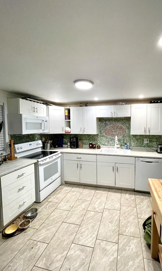 kitchen featuring white cabinetry, sink, and white appliances