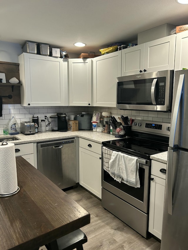 kitchen featuring white cabinetry, backsplash, and appliances with stainless steel finishes