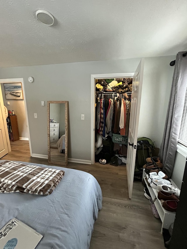 bedroom with dark hardwood / wood-style floors, a textured ceiling, a closet, and a spacious closet