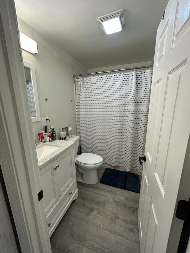 bathroom with hardwood / wood-style flooring, vanity, walk in shower, and toilet