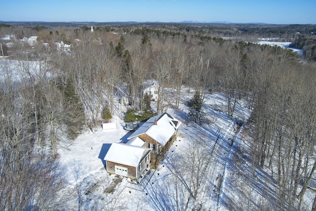 snowy aerial view featuring a wooded view