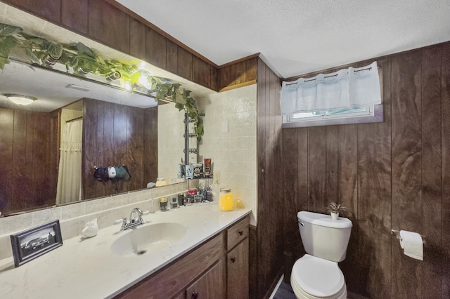 full bath featuring toilet, wooden walls, a textured ceiling, and vanity