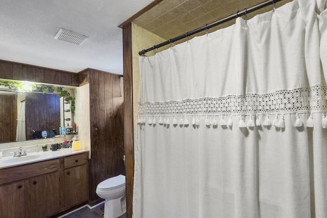 full bath with curtained shower, visible vents, toilet, wooden walls, and vanity