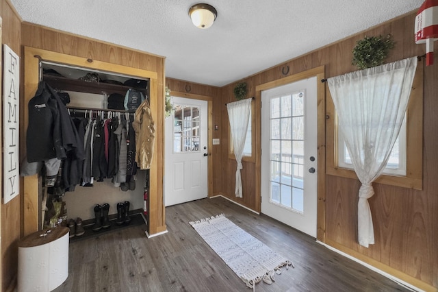 entryway featuring a textured ceiling, wood finished floors, and wooden walls