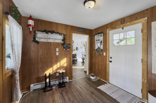 entrance foyer with a baseboard heating unit, a textured ceiling, wood finished floors, and wooden walls