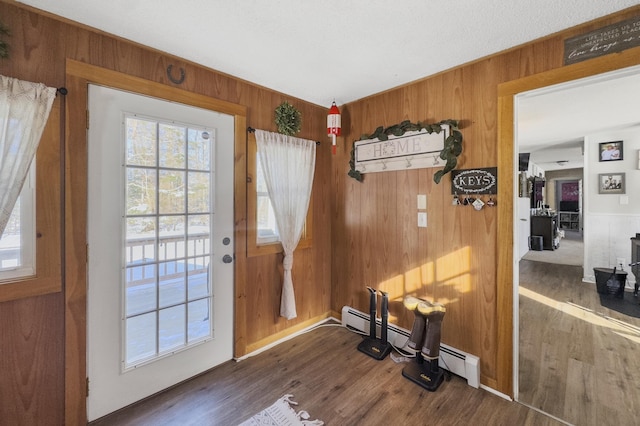 doorway featuring dark wood-type flooring, a baseboard radiator, and wood walls