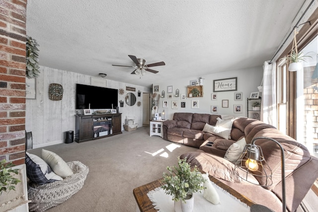 living area with a textured ceiling, carpet floors, and a ceiling fan