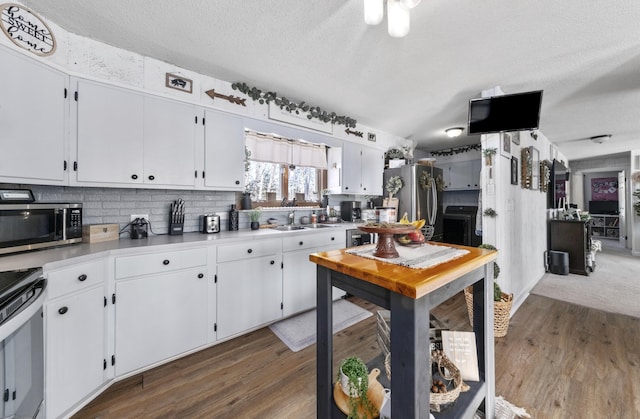 kitchen with stainless steel appliances, white cabinets, light countertops, and dark wood-type flooring