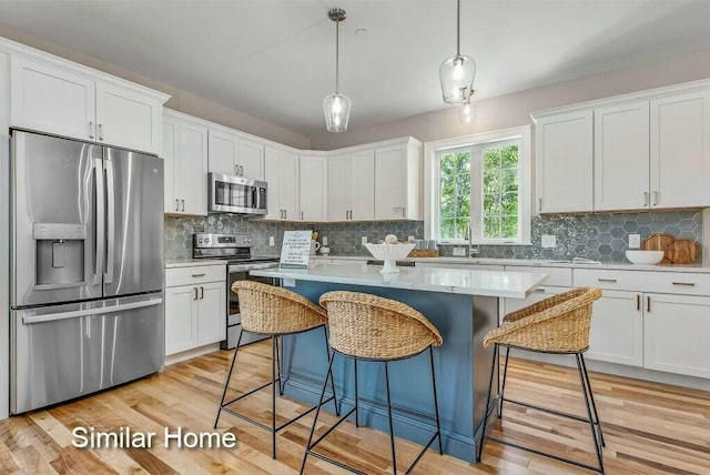 170 Buttonbush Ln Unit 21, Wells, ME 04090 - kitchen featuring stainless steel appliances, a center island, white cabinets, a kitchen breakfast bar, and decorative backsplash