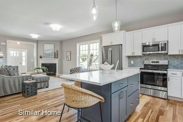 170 Buttonbush Ln Unit 21, Wells, ME 04090 - kitchen with stainless steel appliances, open floor plan, white cabinetry, light wood finished floors, and healthy amount of natural light