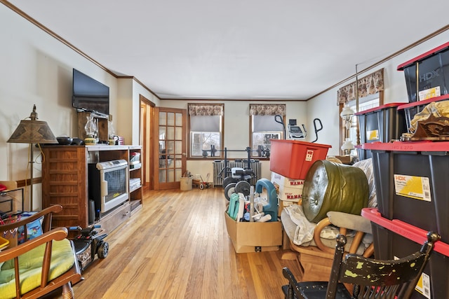 sitting room with radiator heating unit, light hardwood / wood-style flooring, ornamental molding, and a healthy amount of sunlight