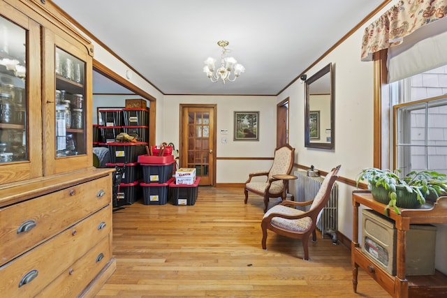 sitting room featuring ornamental molding, radiator heating unit, a notable chandelier, and light wood-type flooring