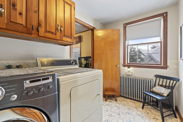 washroom featuring radiator heating unit, cabinets, and washing machine and clothes dryer