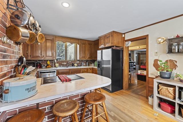 kitchen with tasteful backsplash, sink, a breakfast bar area, stainless steel fridge, and light hardwood / wood-style floors