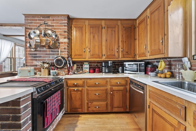 kitchen featuring sink, an inviting chandelier, light hardwood / wood-style flooring, stainless steel appliances, and decorative backsplash