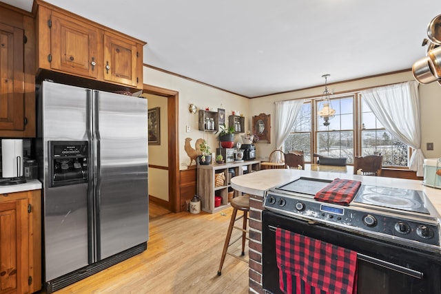 kitchen with black range with electric stovetop, hanging light fixtures, stainless steel refrigerator with ice dispenser, light hardwood / wood-style floors, and ornamental molding