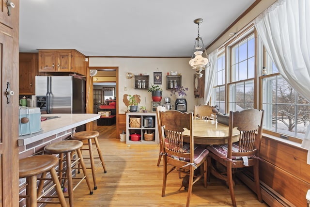 dining space featuring baseboard heating, ornamental molding, and light hardwood / wood-style floors