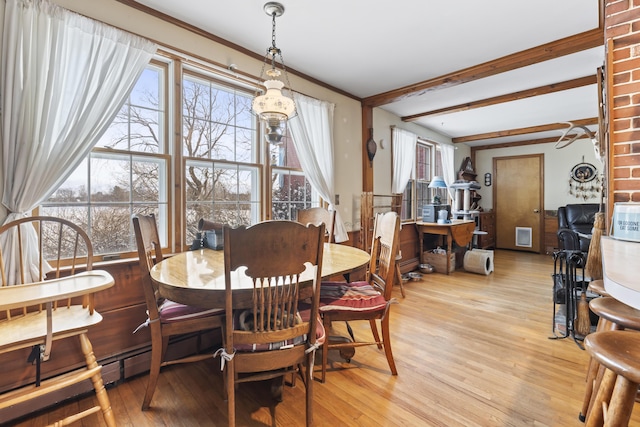 dining space with ornamental molding, beam ceiling, and light hardwood / wood-style flooring