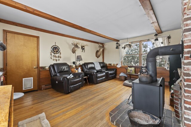 living room with hardwood / wood-style floors, beam ceiling, baseboard heating, and a wood stove