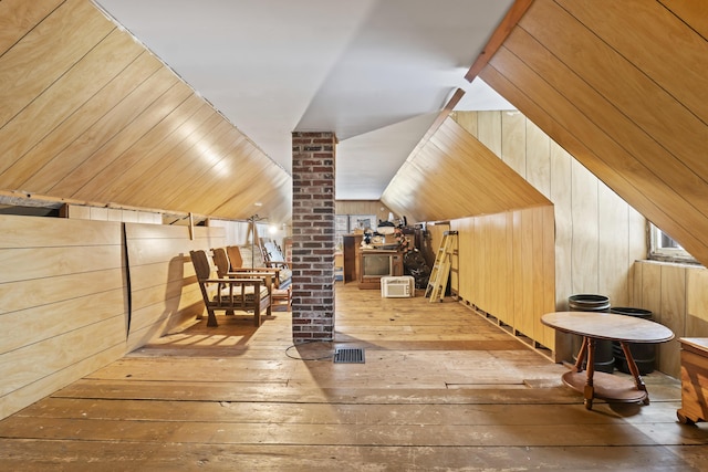 bonus room featuring lofted ceiling, light wood-type flooring, and wood walls