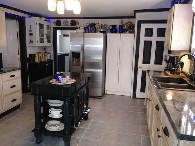 kitchen featuring a sink, stainless steel refrigerator with ice dispenser, tile patterned floors, glass insert cabinets, and white cabinets