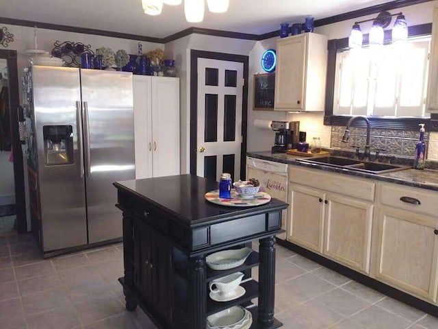 kitchen with light tile patterned floors, stainless steel fridge, a sink, dark countertops, and crown molding