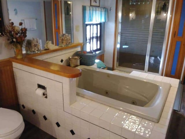 full bath with a jetted tub and toilet