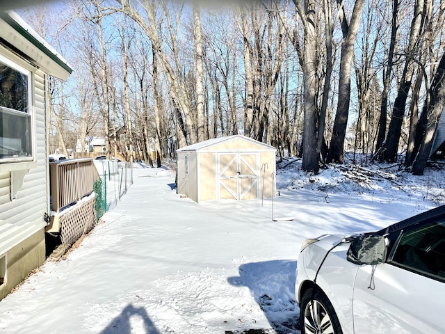 yard layered in snow featuring an outdoor structure and a shed