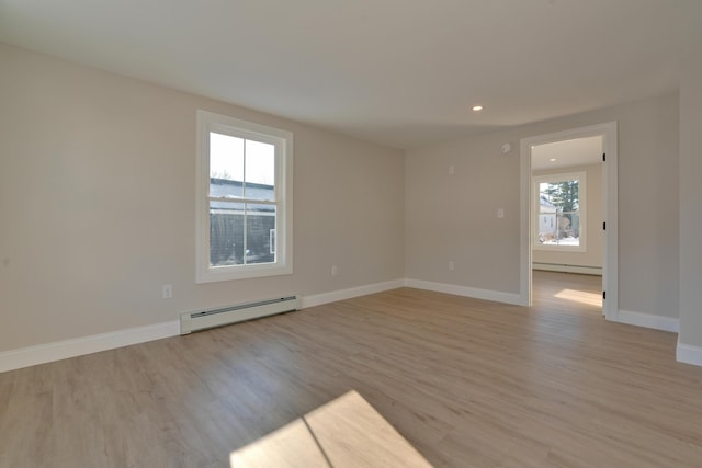 spare room featuring plenty of natural light, light hardwood / wood-style flooring, and a baseboard heating unit