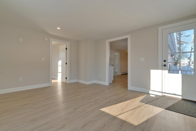 unfurnished room with a baseboard heating unit and light hardwood / wood-style flooring