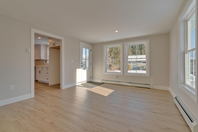 spare room with light hardwood / wood-style floors, a healthy amount of sunlight, and baseboard heating