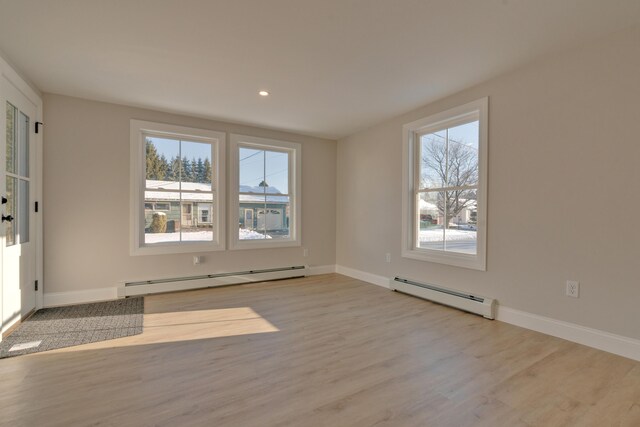 unfurnished room with light wood-type flooring and a baseboard heating unit