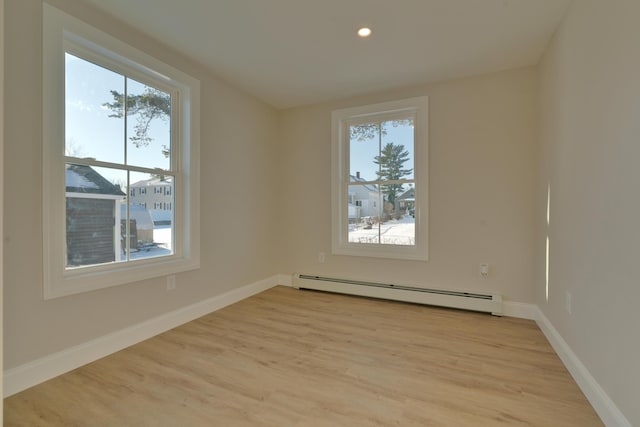 spare room featuring light wood-type flooring and a baseboard heating unit