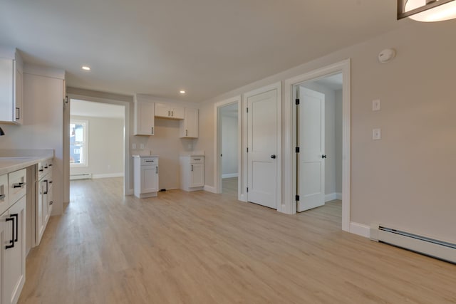 kitchen featuring baseboard heating, white cabinetry, and light hardwood / wood-style flooring