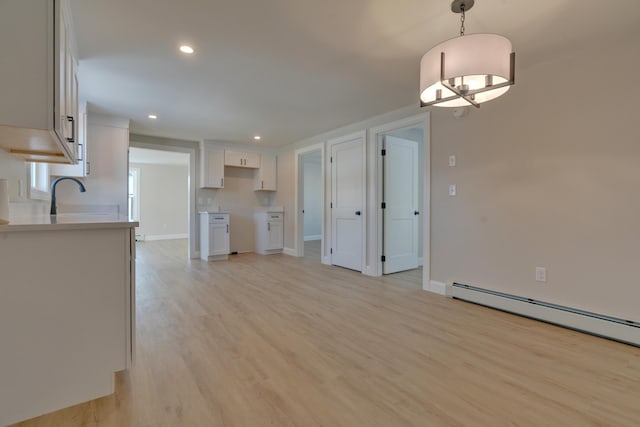 kitchen with white cabinets, hanging light fixtures, light hardwood / wood-style flooring, and a baseboard heating unit