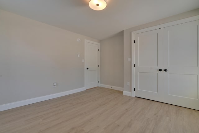 unfurnished bedroom with a closet and light hardwood / wood-style floors